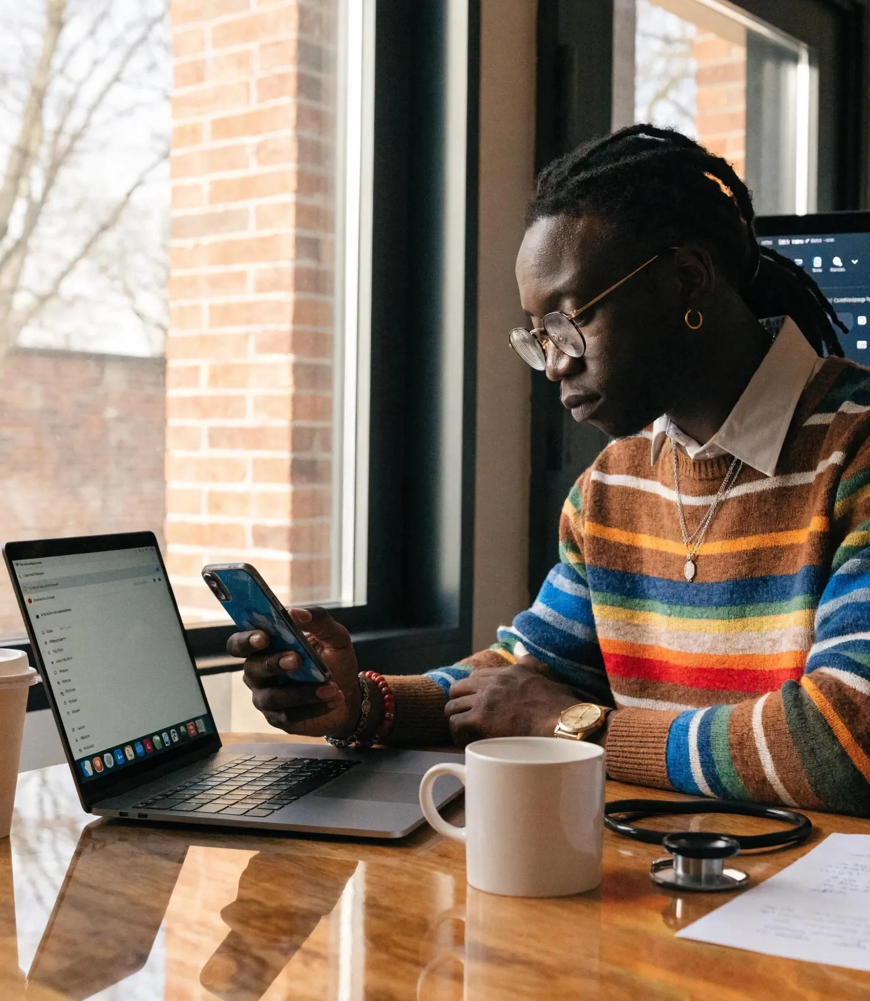 Outsourced help desk specialist checking a support request on his phone at his laptop