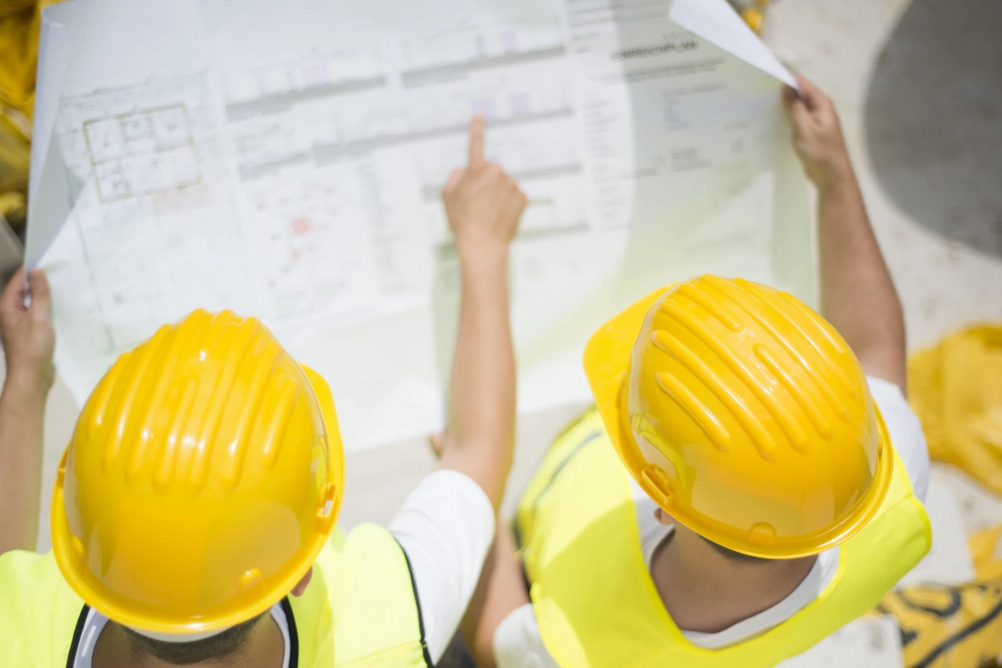 Contractors in hard hats reviewing a blueprint on a job site