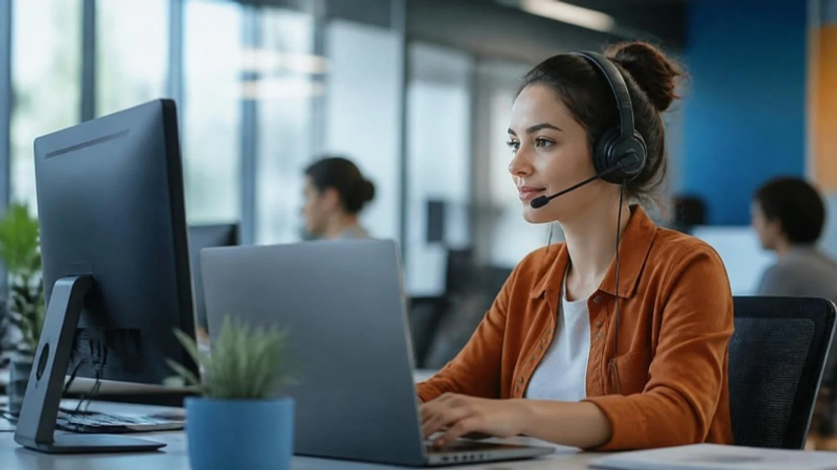 Support agent with a headset answering customer emails and chats at her desk